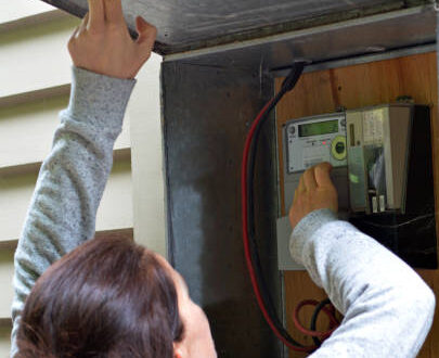 Person som kontrollerar elförbrukningen på en elmätare